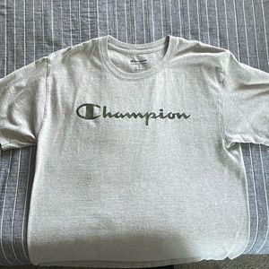 Champion T-Shirt size Medium. Color Gray, with logo on front of it color green.